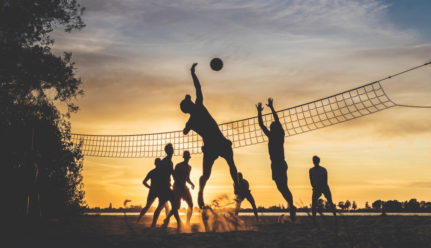 Grupo jogando vôlei de praia ao entardecer